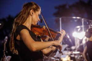 Beautiful woman playing violin at night outdoor concert
